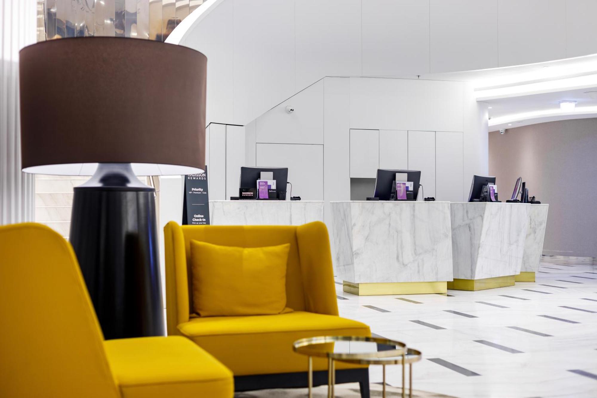 Radisson Blu Resort Świnoujście מראה חיצוני תמונה The photo shows a modern reception area, likely of a hotel or a similar establishment. In the foreground, there are two yellow armchairs with soft cushions, situated around a small round table with a minimalist design. Behind the seating area, there 