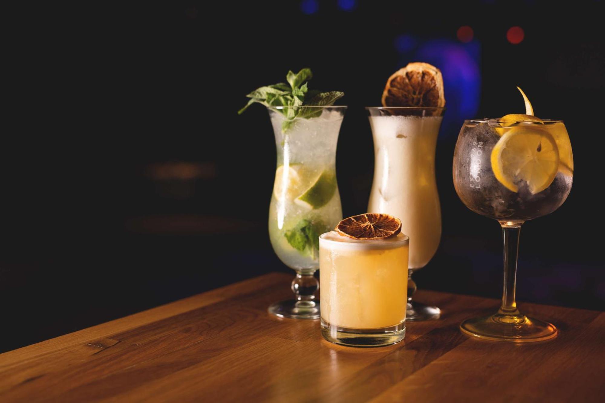 Radisson Blu Resort Świnoujście מראה חיצוני תמונה The photo showcases a collection of four different cocktails displayed on a wooden table. 

1. **Mojito**: A tall glass filled with lime slices, mint leaves, and a clear liquid, likely rum-based, garnished with fresh mint.
2. **Creamy Cocktail**: A s