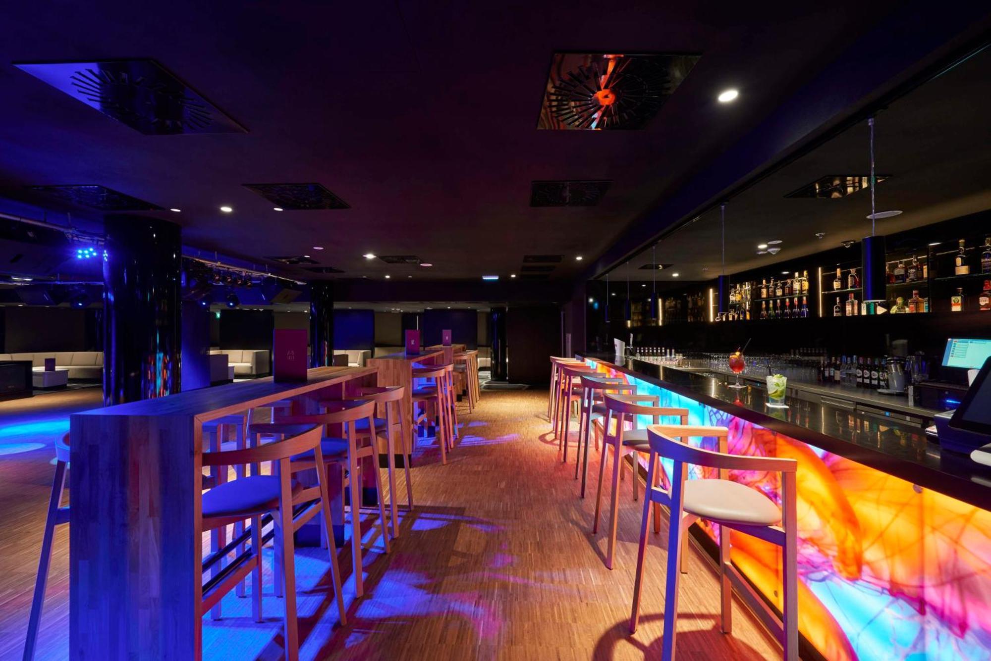 Radisson Blu Resort Świnoujście מראה חיצוני תמונה The photo depicts a modern bar interior with a sleek and contemporary design. There are high wooden stools positioned along a bar counter, which features vibrant, colorful lighting underneath. The bar area is dimly lit, creating a nightlife ambiance,