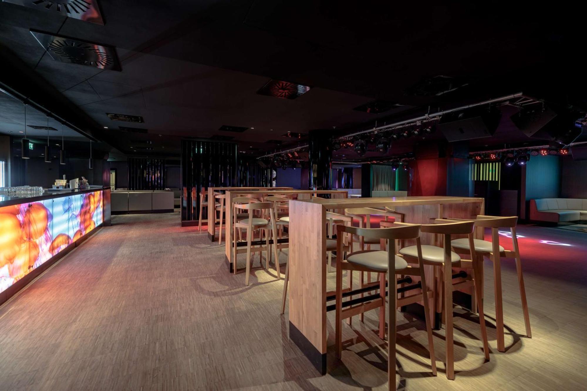 Radisson Blu Resort Świnoujście מראה חיצוני תמונה The photo shows an interior space that appears to be a bar or lounge. It features a modern design with a dark color scheme. There are several wooden high-top tables with matching stools arranged in the area. In the background, there is a bar counter,