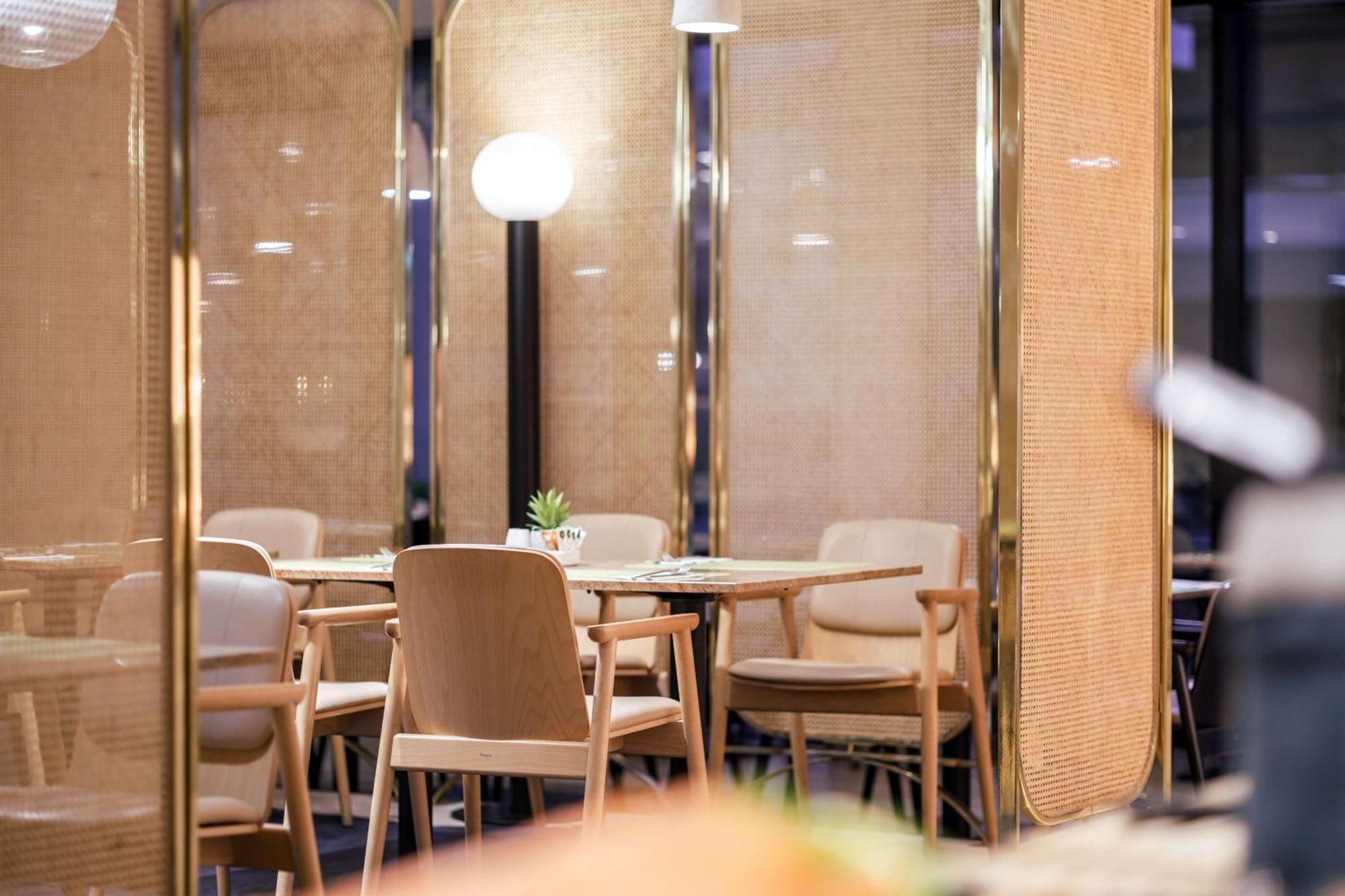 Radisson Blu Resort Świnoujście מראה חיצוני תמונה The image shows an interior space, likely part of a restaurant or café. There are several wooden chairs arranged around tables, and the overall decor features soft lighting and warm colors. The walls appear to be partially covered with a woven materi